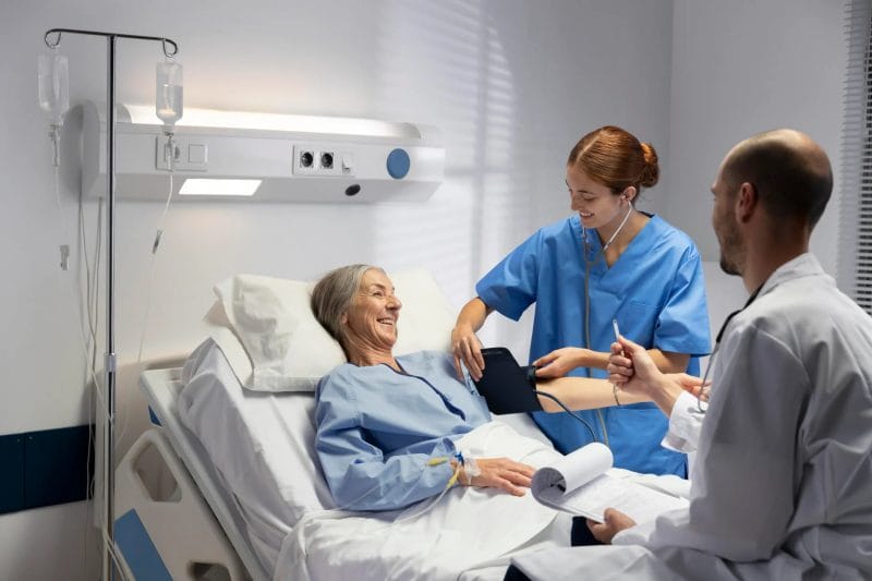 Two nurses helping a patient in a hospital bed
