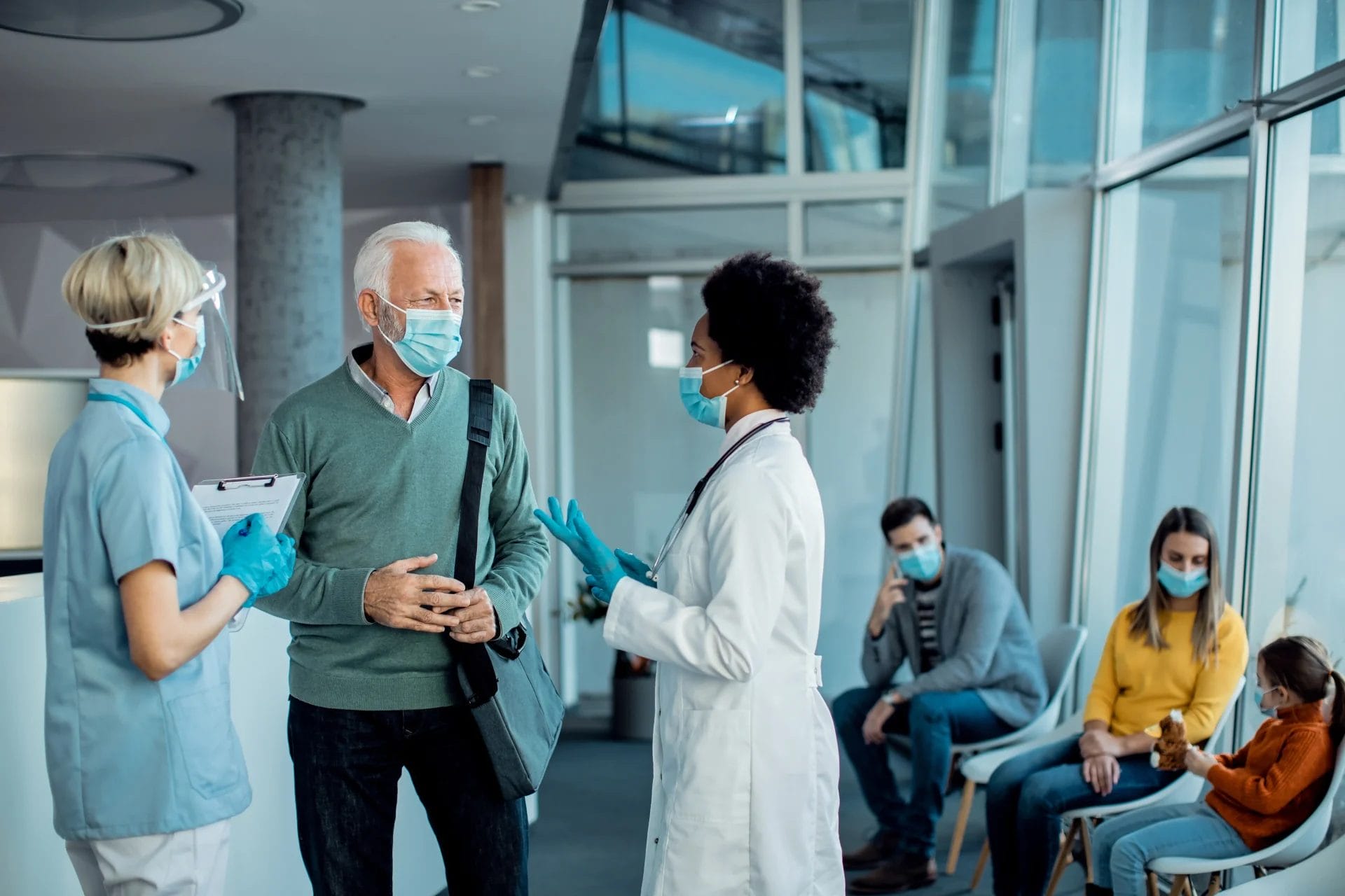 Two nurses talking to a man at reception