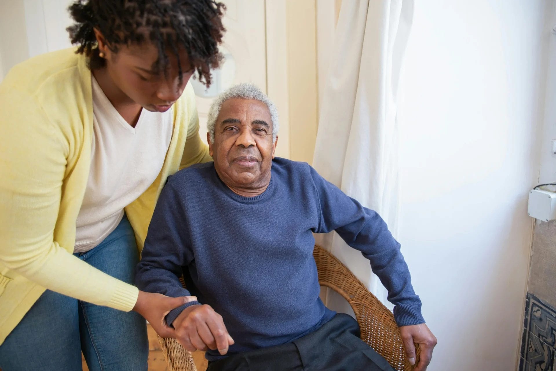 A district nurse helping her patient stand up