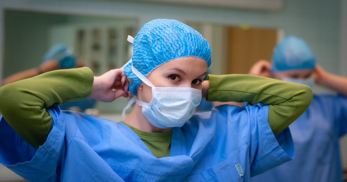 A nurse putting her face mask on